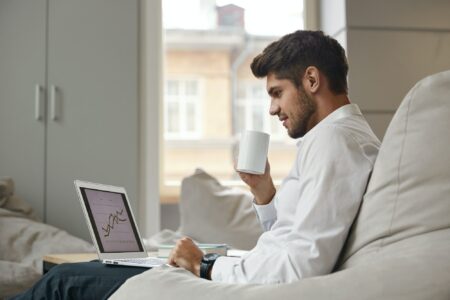 Businessman drink coffee and watch graph on laptop Businessman drink coffee and watch graph on laptop
